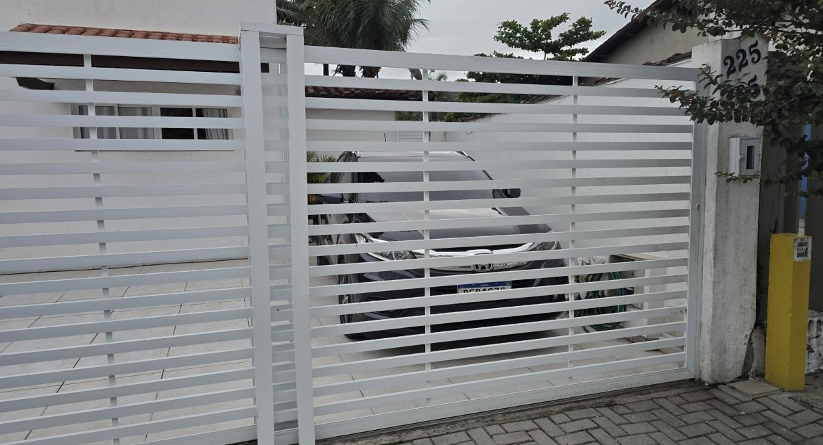 Fachada externa de casa de temporada em Juquehy em condomínio fechado com portão branco e calçada pavimentada