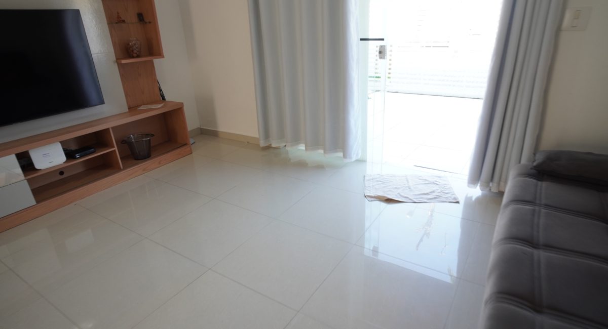 Detalhe do piso em porcelanato limpo e arejado da sala de estar em casa de aluguel em Juquehy com vista para a porta de entrada.