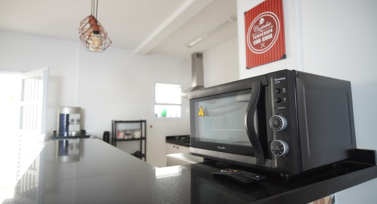 ozinha equipada em casa de temporada em Juquehy com micro-ondas Brastemp, cooktop, bancada de granito e utensílios completos.