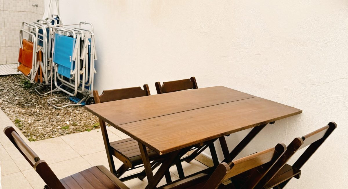 Mesa dobrável de madeira em área externa coberta da casa em Juquehy, ideal para o café da manhã.